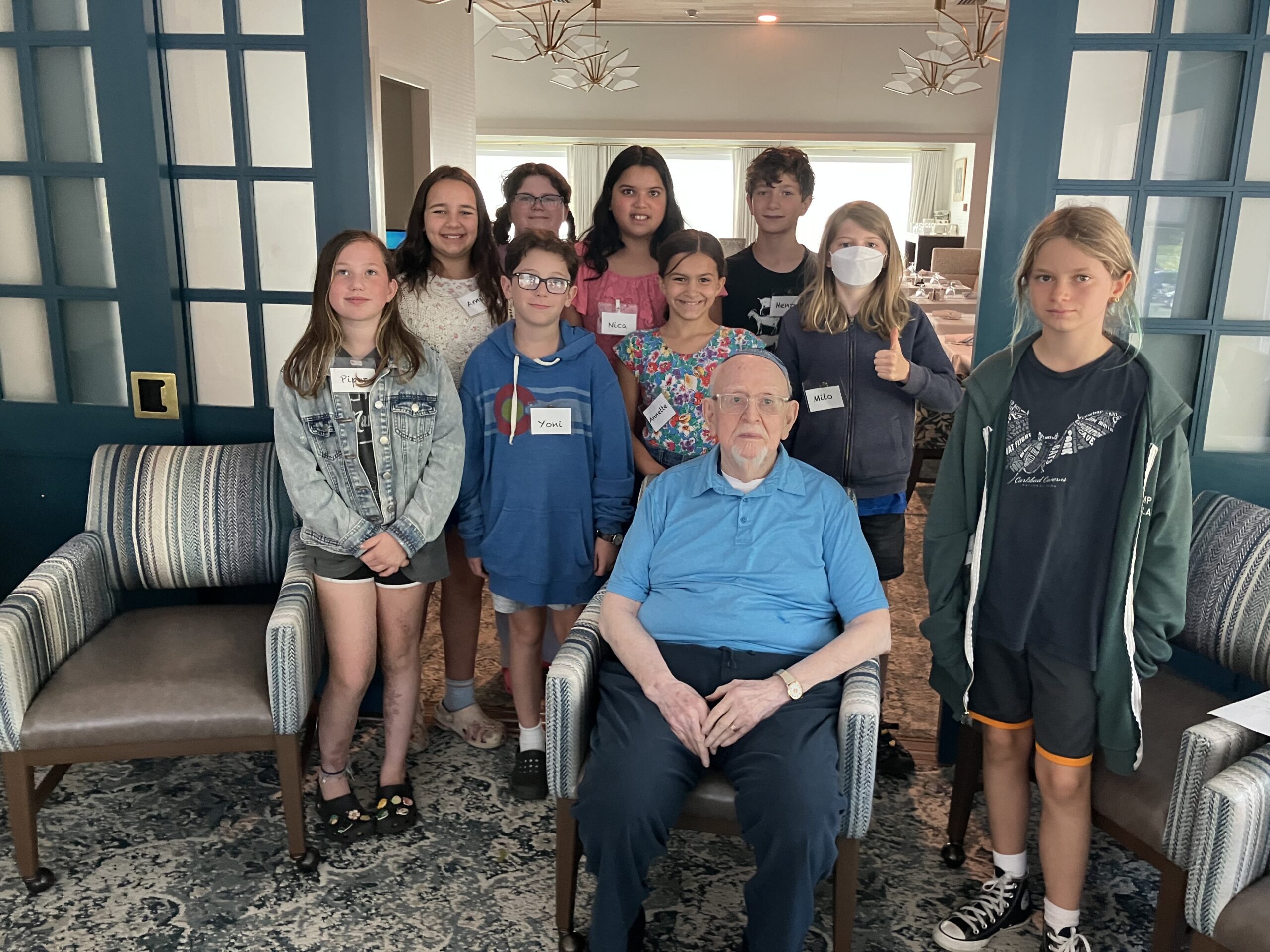 Kitah vav students standing with Rabbi Lander in a wheelchair