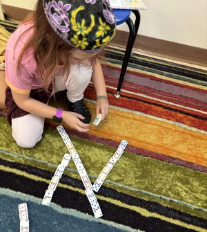 Student making an aleph out of dominoes